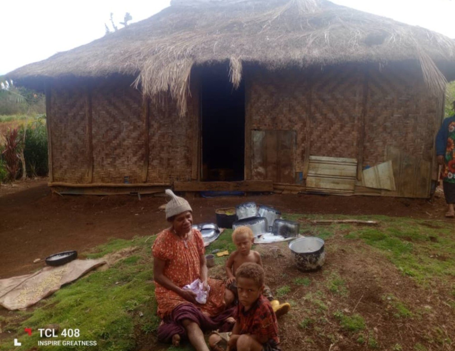 A grandmother and two children outside their thatched home in Kun Valley